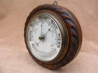 Antique aneroid barometer with curved thermometer